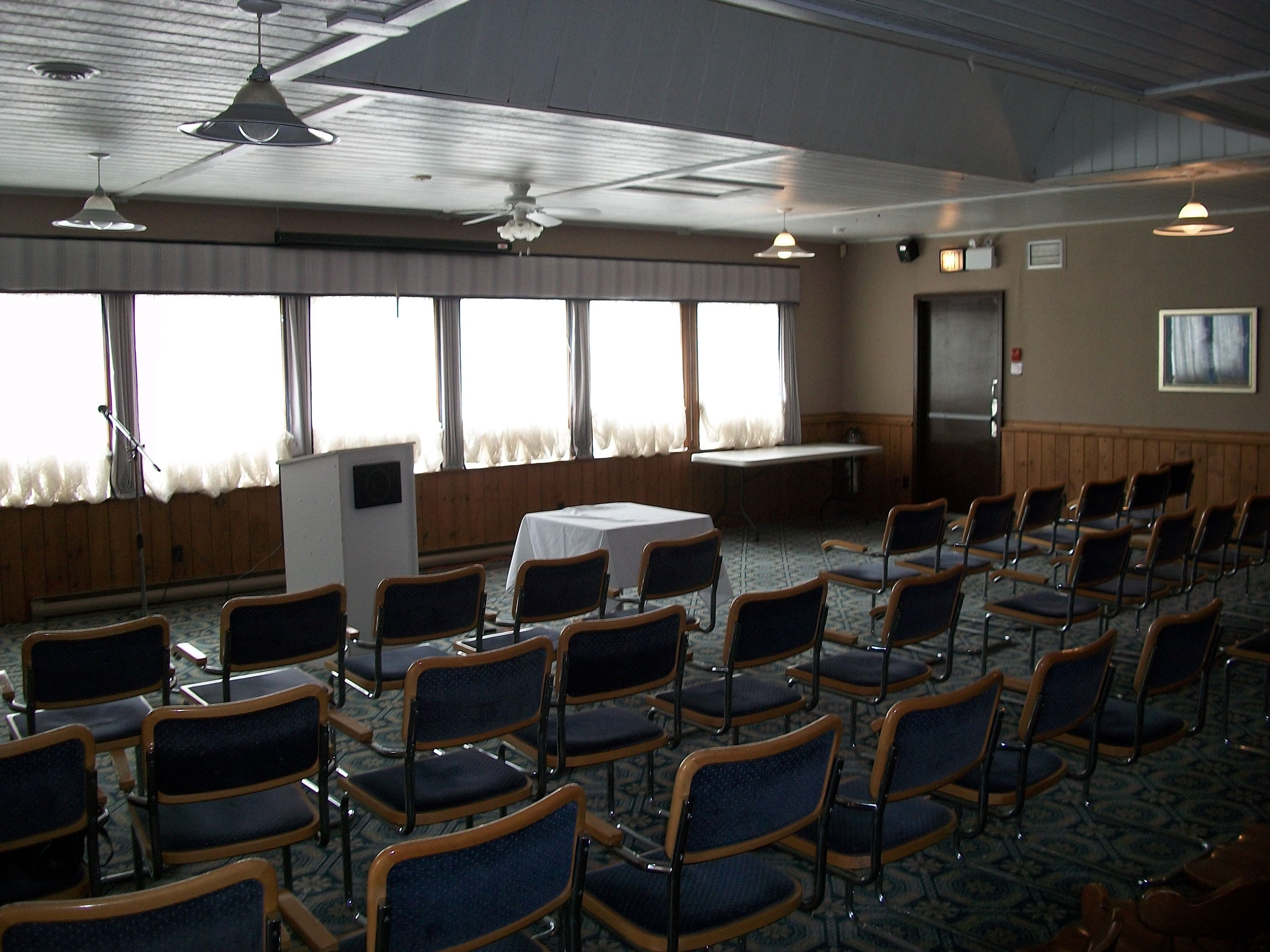 Un salón de conferencias con filas de sillas, una mesa y un atril.