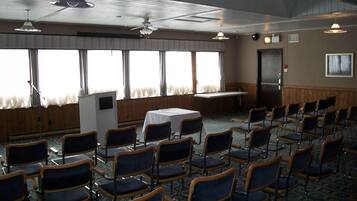 A conference room with rows of chairs, a table, and a podium.