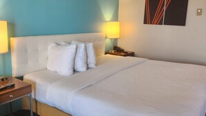 Camera d'albergo con un letto grande, due abat-jour, un comodino e un'opera d'arte appesa al muro.