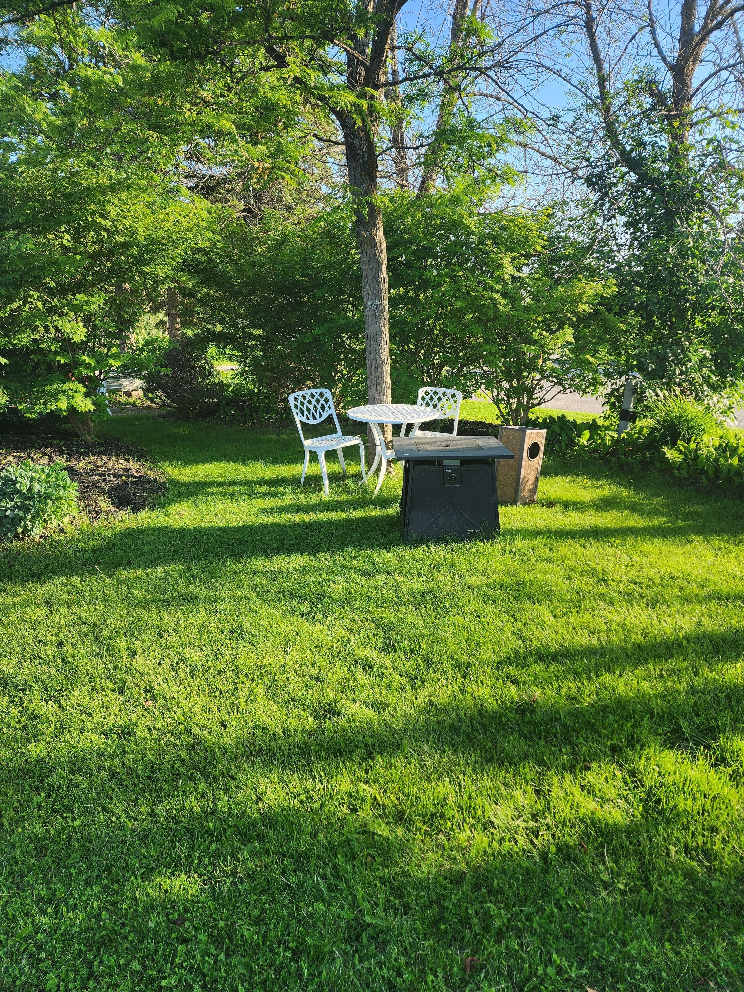 A grassy outdoor area with a table and two chairs.