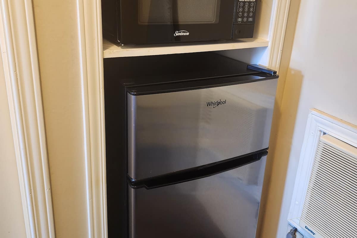 Una cocina compacta con un microondas y un refrigerador negros.