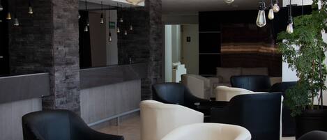 A modern lobby with leather sofas, a reception desk, and hanging pendant lights.
