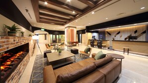 A modern lobby with a fireplace, seating area, and a bar.