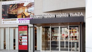 The exterior of Washington Hotel Plaza with a large sign, a glass entrance, and a tiled floor.