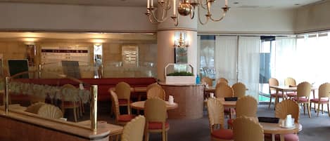 Un lobby de hotel con una lámpara de araña imponente, una recepción y un área de descanso con mesas y sillas redondas.