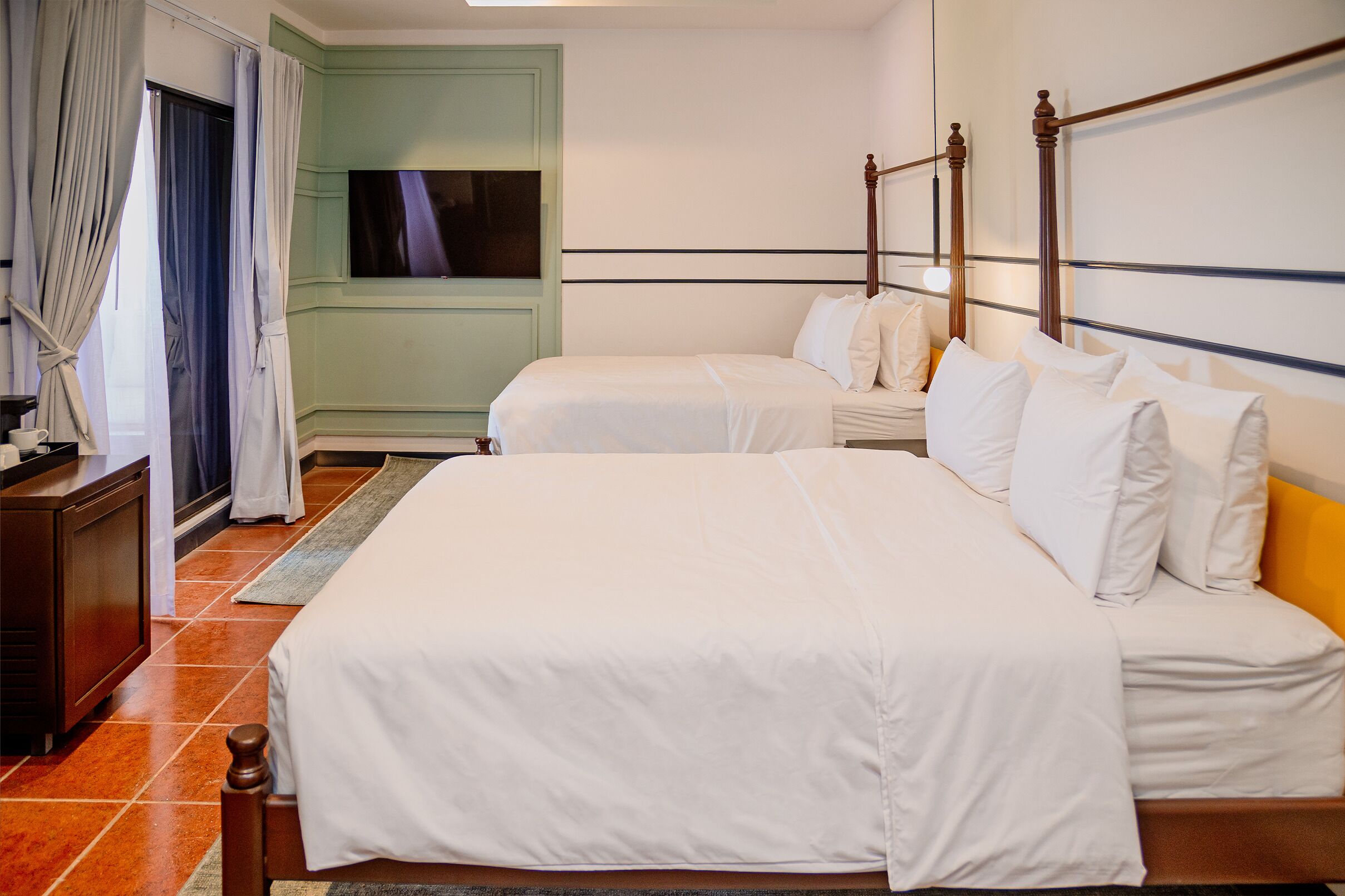 A hotel room with two beds, a TV, and a green wall.
