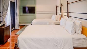 A hotel room with two beds, a TV, and a green wall.