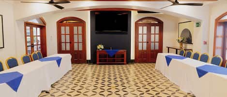 A conference room with a geometric patterned floor, white tables with blue tablecloths, and wooden doors.
