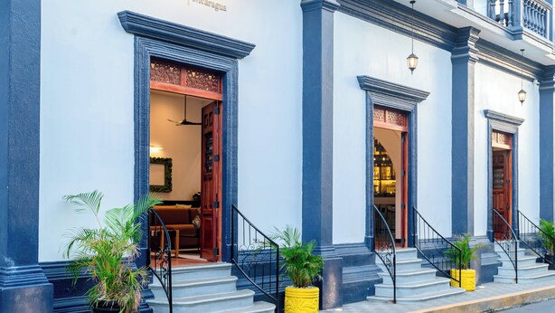 A hotel facade with large windows, a sign reading "Voco Lake Nicaragua," and a staircase leading to the entrance.