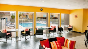 A hotel lobby with a pool view, outdoor seating, and a clock on the wall. - Résidence Saskia (Cazaubon)