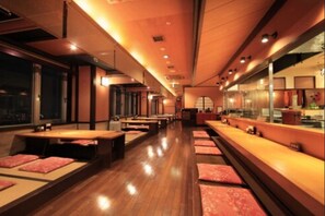 Un restaurante con suelo de madera, asientos acolchados rojos y una barra larga.