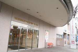 The exterior of the Washington Hotel Plaza with a tiled facade, large glass entrance doors, and a bench outside. - Kofu Washington Hotel Plaza (Kofu)