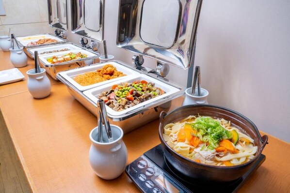 Un bufé con diversos platos y una olla caliente.