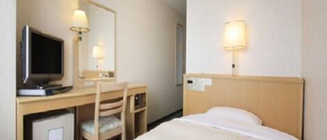 A hotel room with a bed, a desk with a computer, a chair, a television, and a mirror.