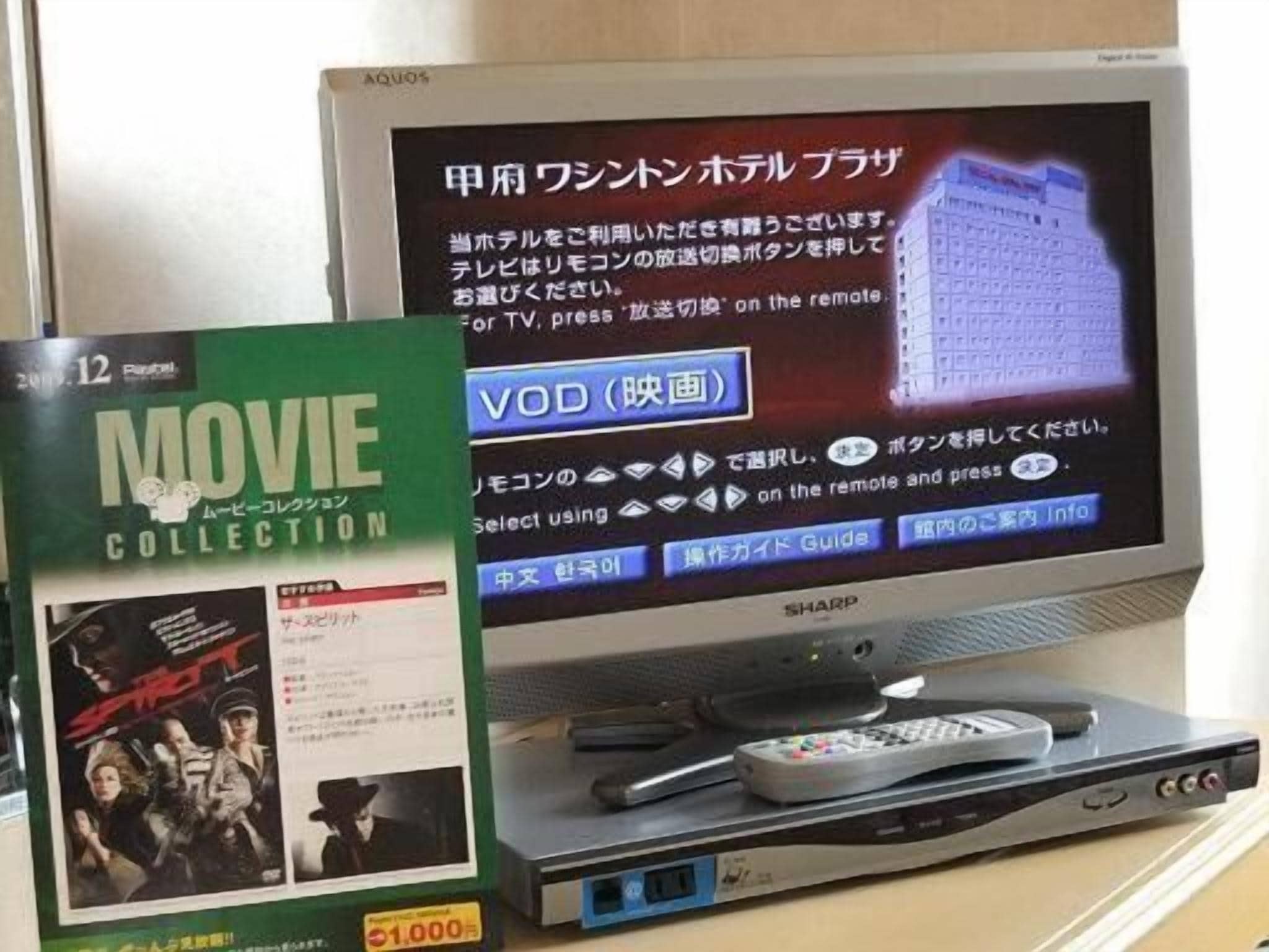 A television displaying a menu interface in Japanese, a DVD player with a remote control, and a DVD cover titled "MOVIE COLLECTION" with a price tag of 1,000 yen.
