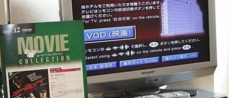 A television displaying a menu interface in Japanese, a DVD player with a remote control, and a DVD cover titled "MOVIE COLLECTION" with a price tag of 1,000 yen.