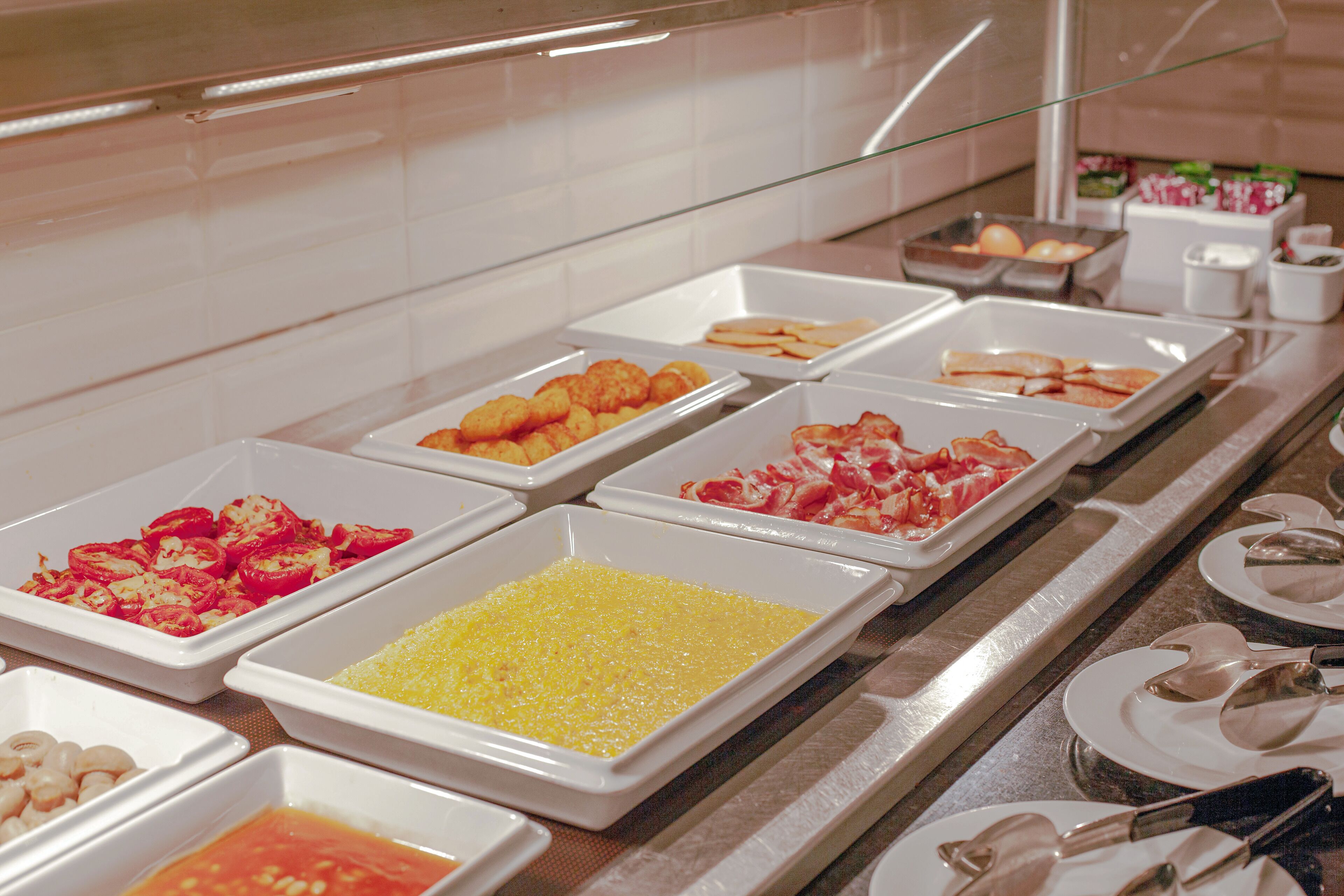 A buffet with various food items in trays, including what appears to be scrambled eggs, shrimp, and other dishes.