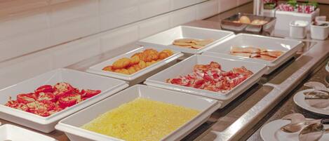 A buffet with various food items in trays, including what appears to be scrambled eggs, shrimp, and other dishes.