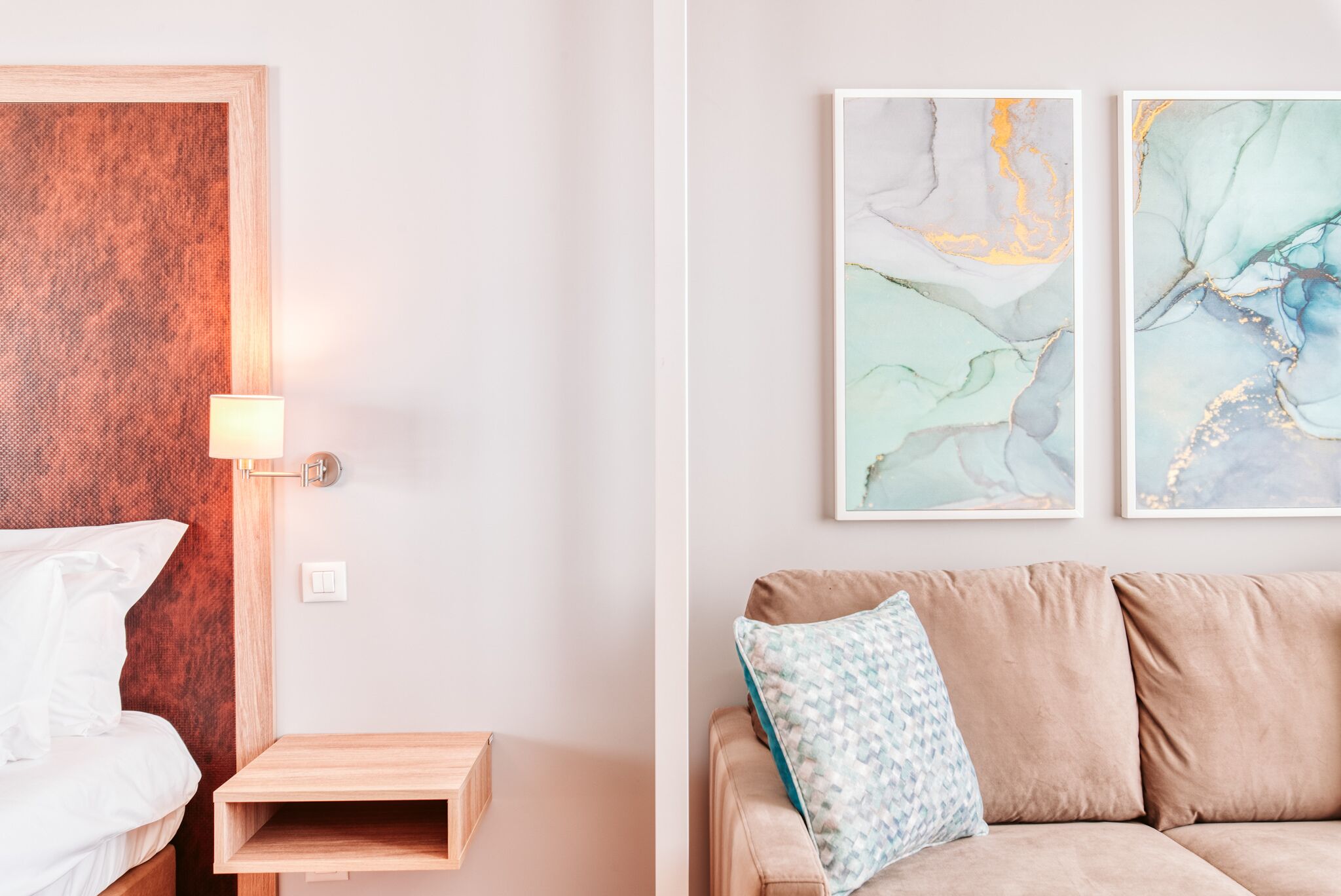 Une chambre à coucher avec une tête de lit en bois, une table de chevet avec une lampe, un lit avec du linge de lit blanc et une petite étagère en bois.