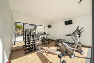 A modern gym with exercise equipment, a bench, and a large window offering a view of the outdoors.