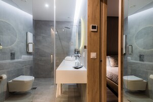 A modern bathroom with a glass-enclosed shower, a white sink, and a wooden door.