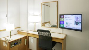 Ein Hotelzimmer mit Schreibtisch, Stuhl, Telefon, Lampe, Spiegel und Fernseher, der eine Karte zeigt.