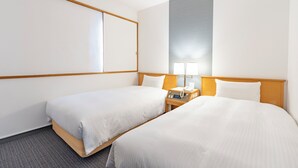 Ein Hotelzimmer mit zwei Betten, einem Nachttisch mit Lampe und einem großen Fenster.