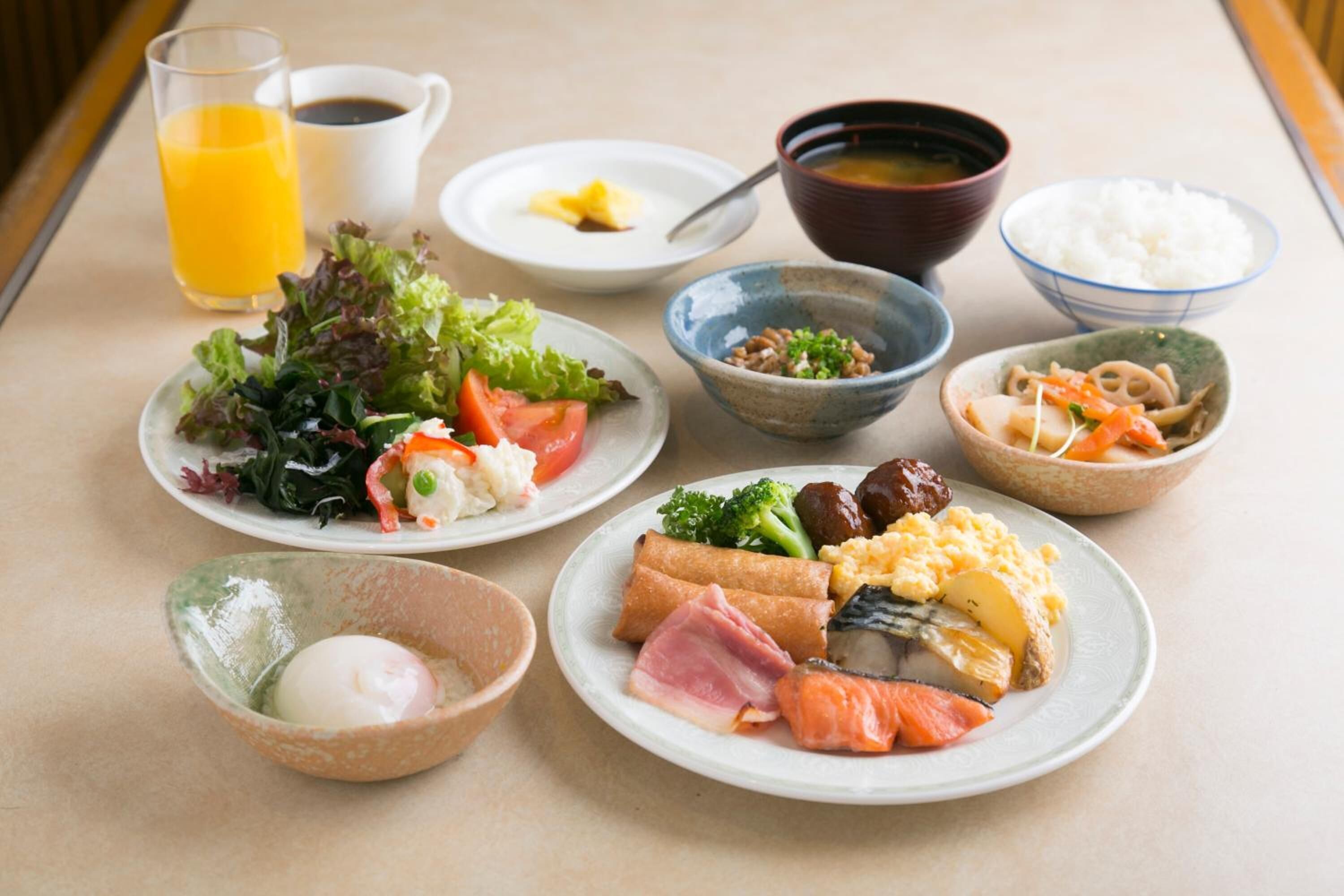A table with various dishes, including a salad, soup, rice, and a bowl of eggs.