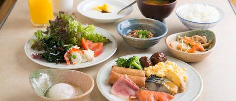 A table with various dishes, including a salad, soup, rice, and a bowl of eggs.