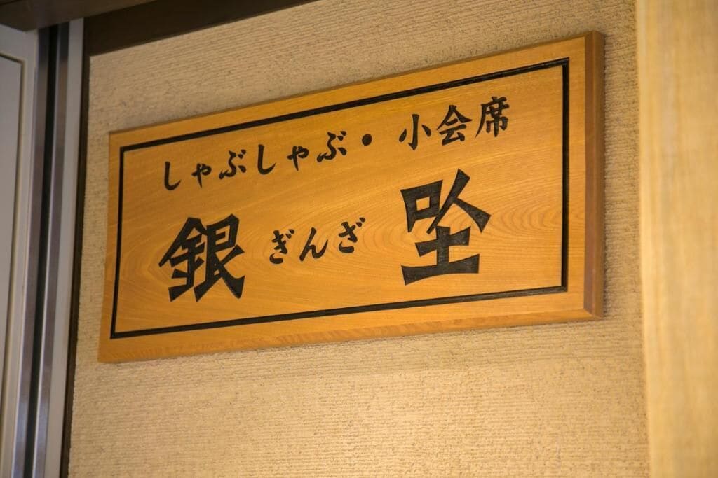 A wooden sign with Japanese characters, likely indicating a room or area name.