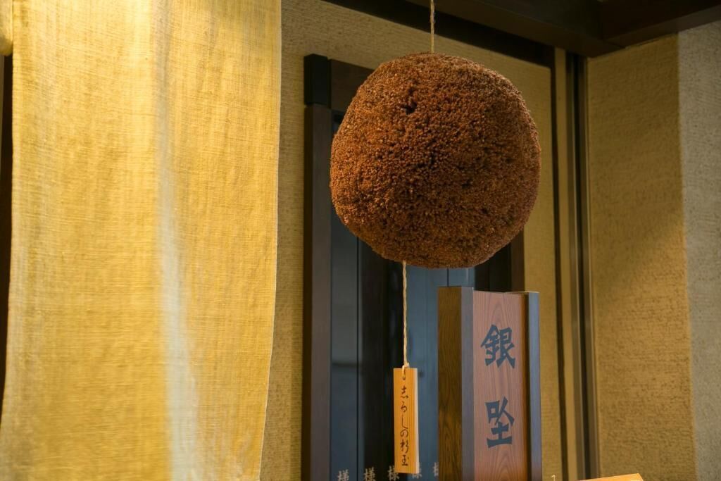 A hanging spherical object with Japanese characters, a vertical wooden panel with text, and a curtain.