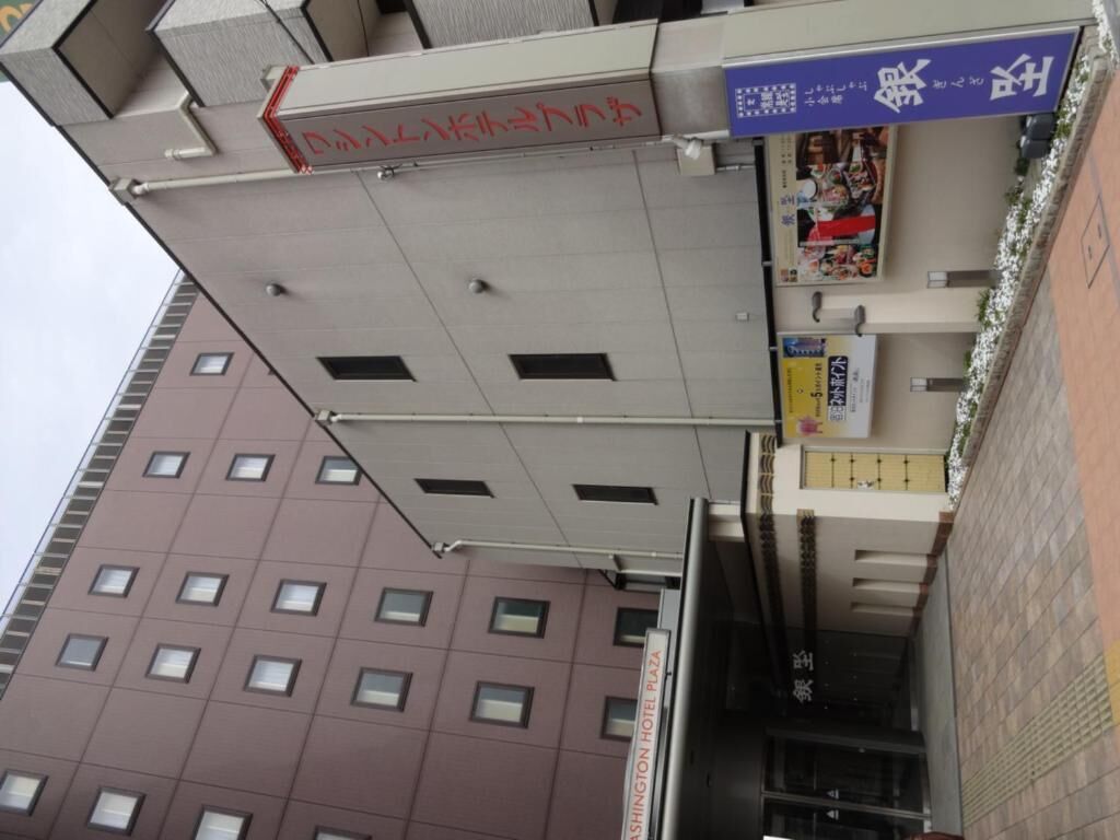Ein Hotel mit einem Schild, auf dem "Washington Hotel Plaza" steht, und einem weiteren Schild mit japanischen Schriftzeichen.