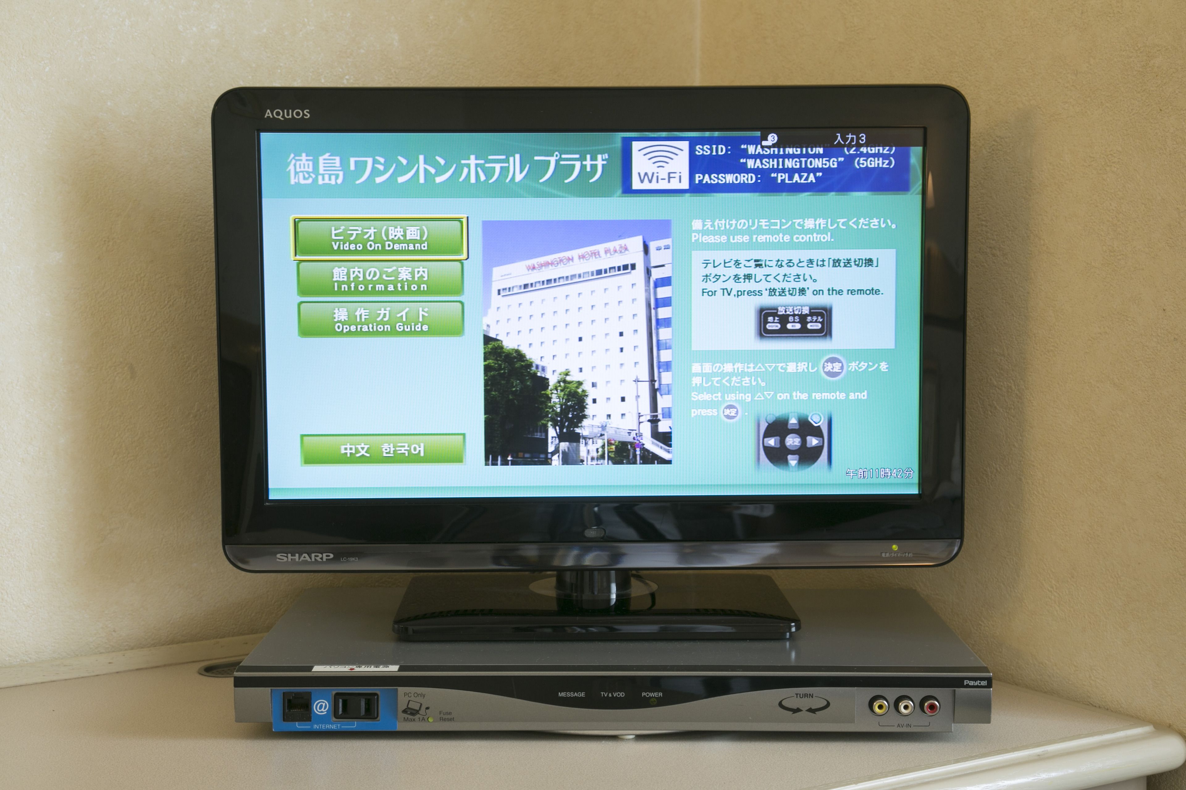 A Sharp TV on a stand with a remote control.
