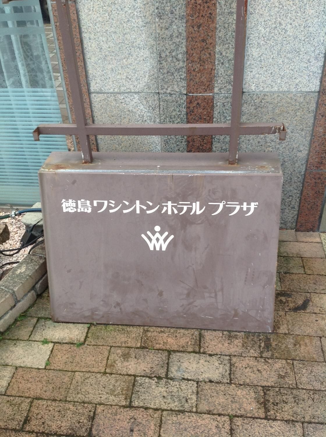 A grey metal structure with Japanese text and a white icon, possibly a hotel or service sign.