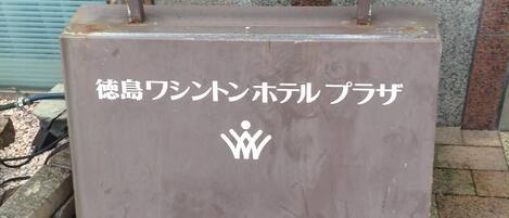 A grey metal structure with Japanese text and a white icon, possibly a hotel or service sign.