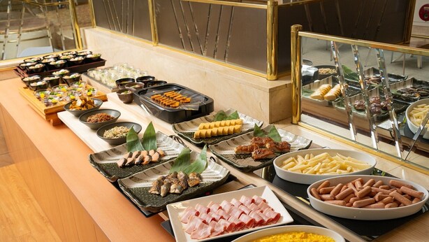 A buffet with various dishes including sushi, sashimi, and other Asian cuisine.
