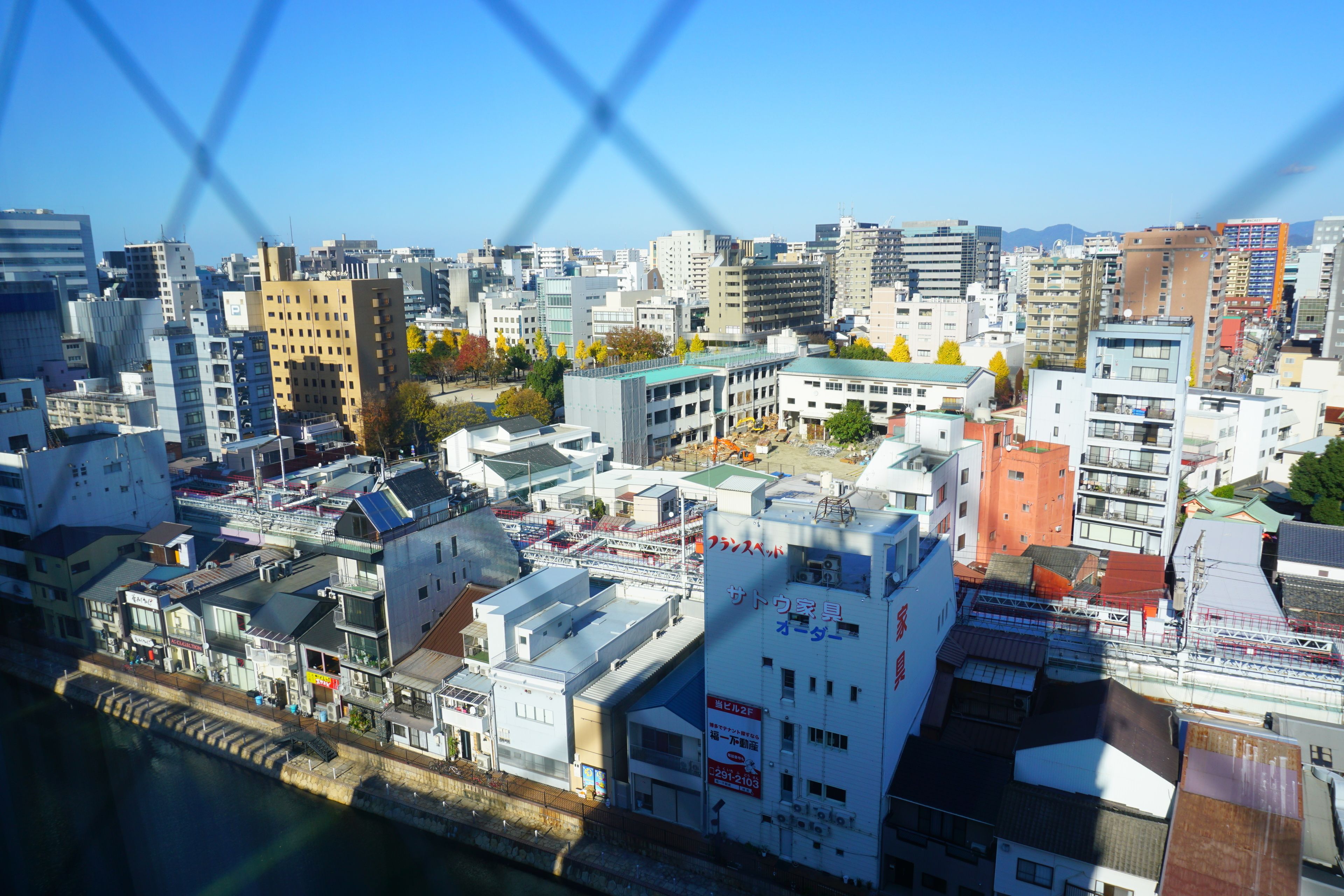 Une vue urbaine comprenant divers bâtiments, dont un grand bâtiment blanc sur lequel on peut voir une enseigne dans une langue étrangère.