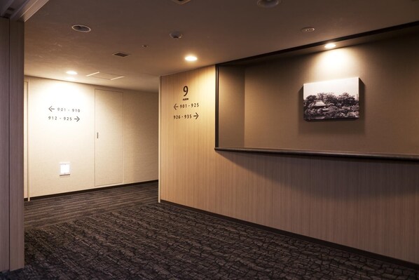 A hotel hallway with directional signs for room numbers 901-910, 912-925, and 926-935.