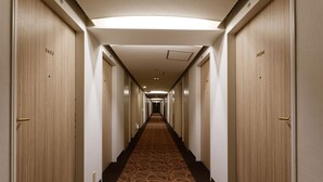 Un couloir d’hôtel avec des portes en bois numérotées 1403 et 1404, un sol recouvert de moquette et un éclairage encastré.