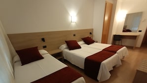 A hotel room with two single beds, each with a red throw blanket and white bedding. There is a wooden headboard, a nightstand, and a desk with a chair. A wall-mounted light fixture is visible above the bed. - Hotel Vilobí (Vilobi d'Onyar)