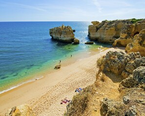 A beach with clear blue water, rocky formations, and a sandy shore. - Vila Channa (Albufeira)