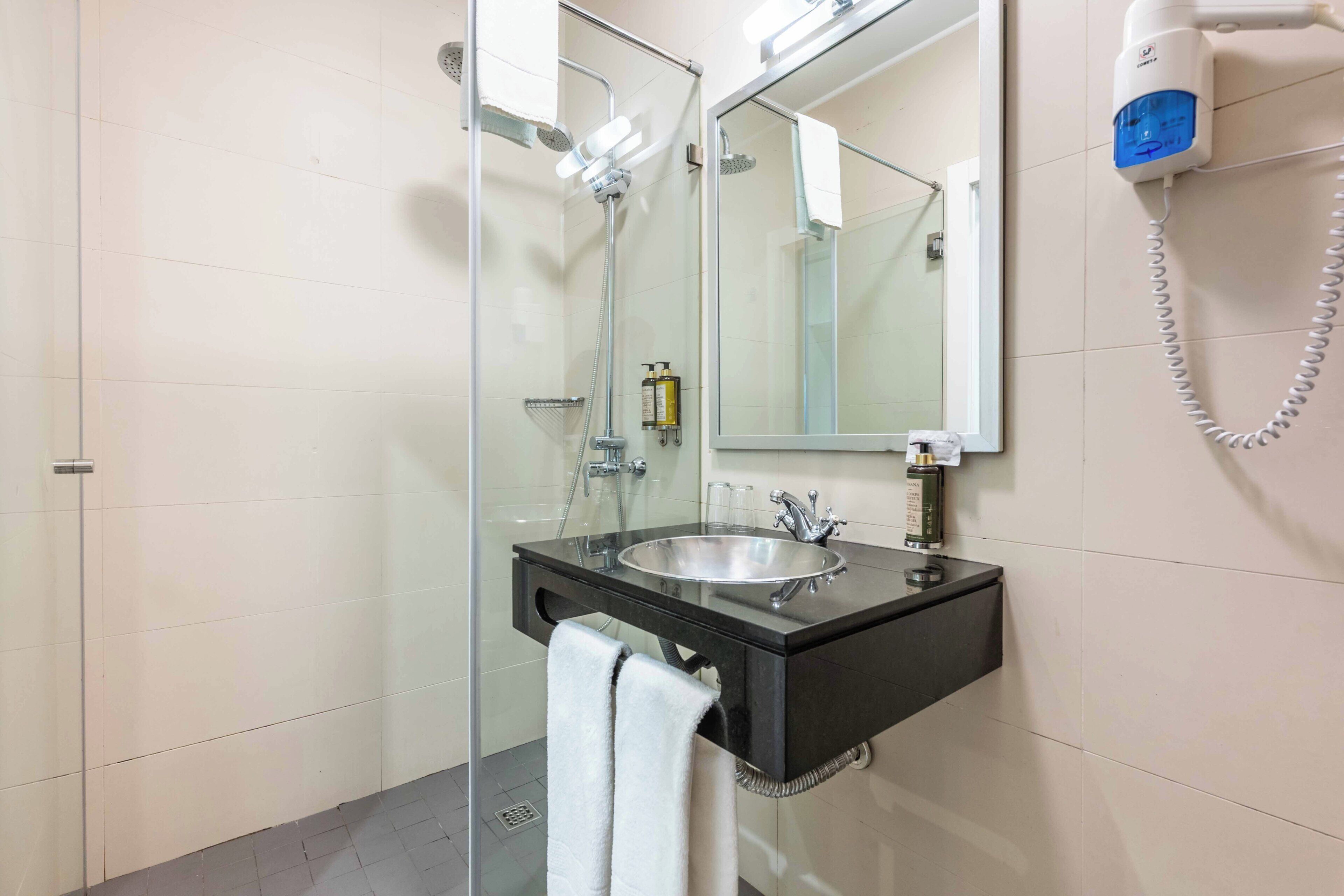 A modern bathroom with a glass shower enclosure, a black vanity with a sink, and a mirror.