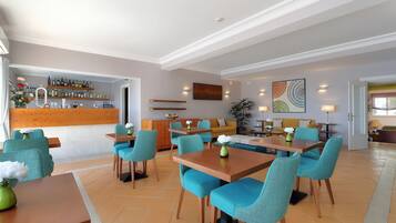 A modern hotel lobby with a bar area, seating arrangements, and a dining section.