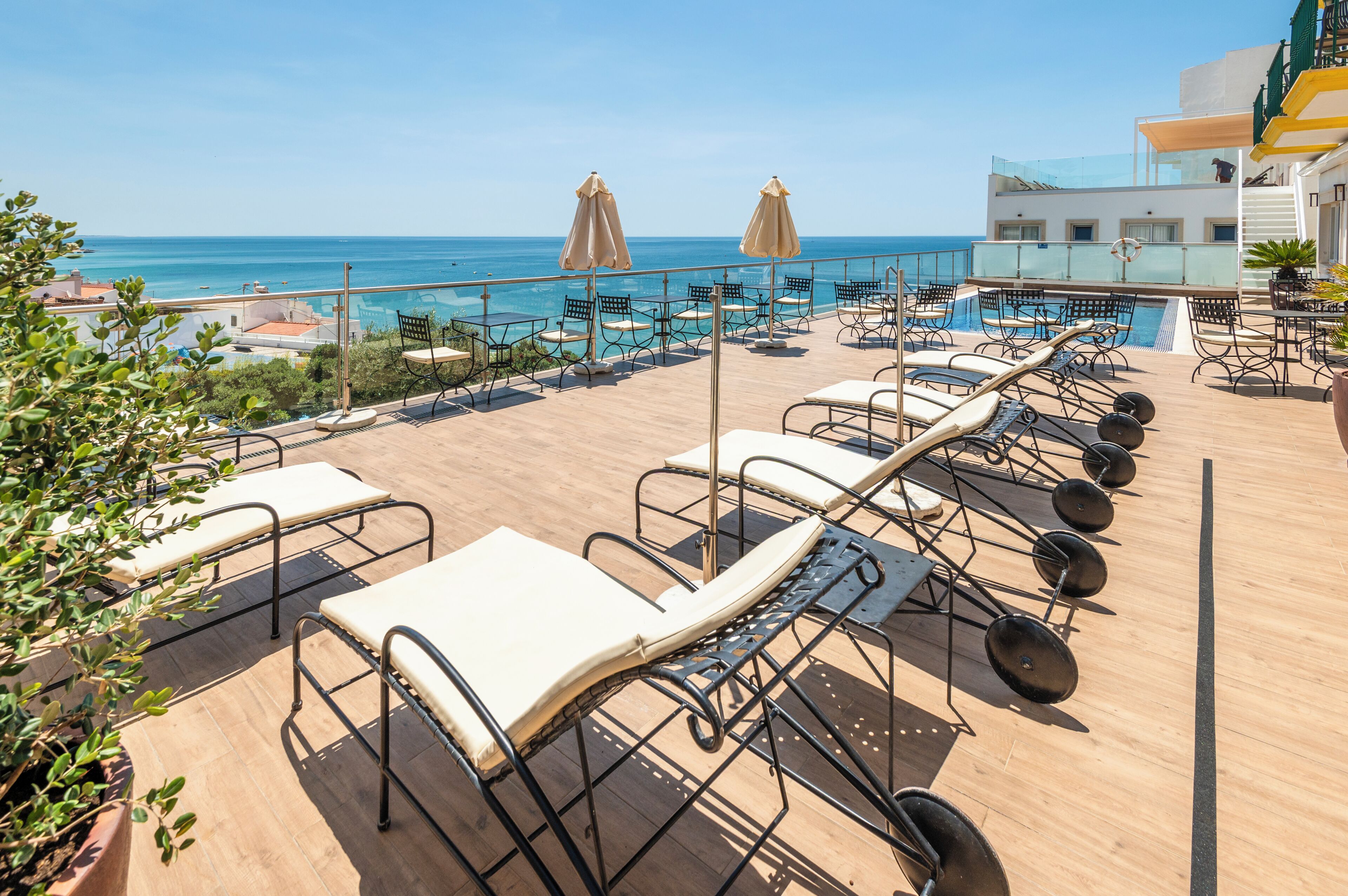A rooftop terrace with lounge chairs, a pool, and a view of the sea.
