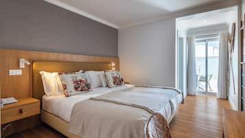 A bedroom with a large bed, wooden headboard, bedside table, and a view of the outdoors.