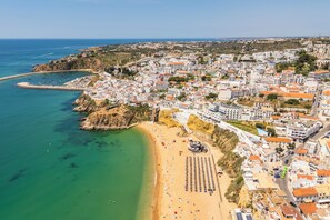 Vue aérienne d’une ville côtière avec une plage, des bâtiments et une côte rocheuse.