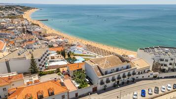 Un pueblo costero con playa, edificios de techo rojo y vistas despejadas al mar.