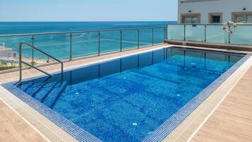 A swimming pool with a glass barrier, a lifebuoy, and a view of the ocean.