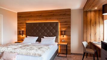 A modern bedroom with a tufted headboard, a wooden accent wall, a desk, and a chair.