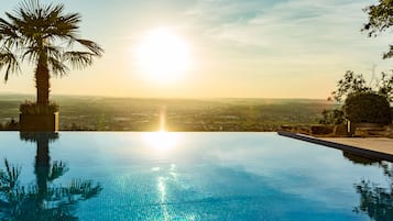 Una piscina al aire libre, sombrillas, sillones reclinables de piscina